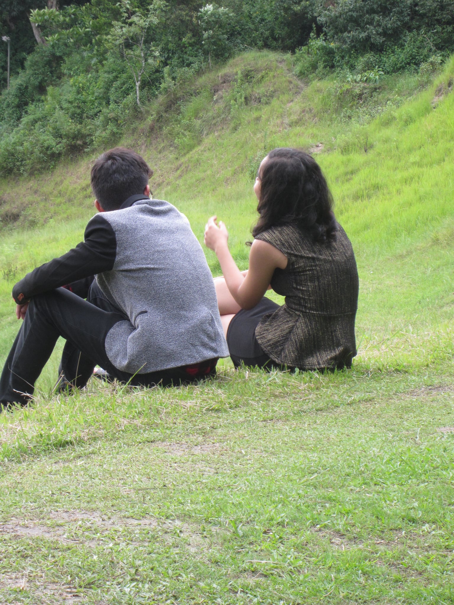 Abhishek and Alyssa sitting together on a grassy hillside