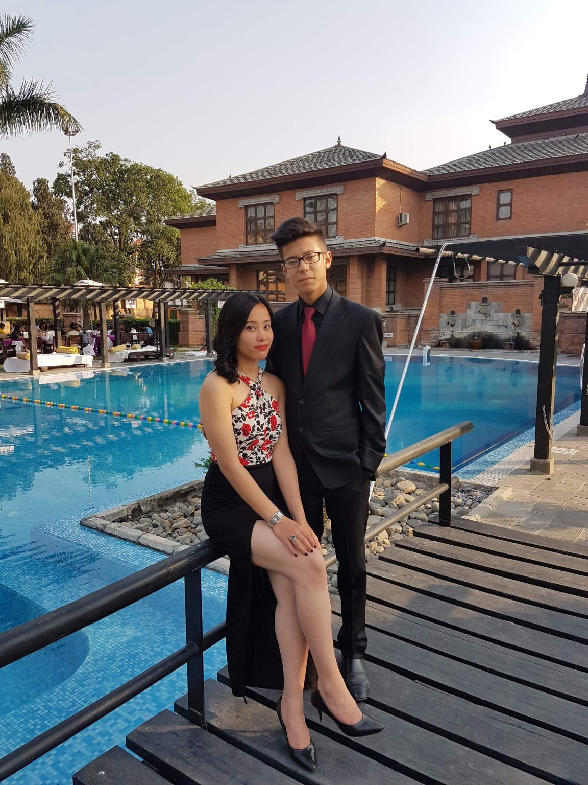 Abhishek and Alyssa dressed up beside a swimming pool